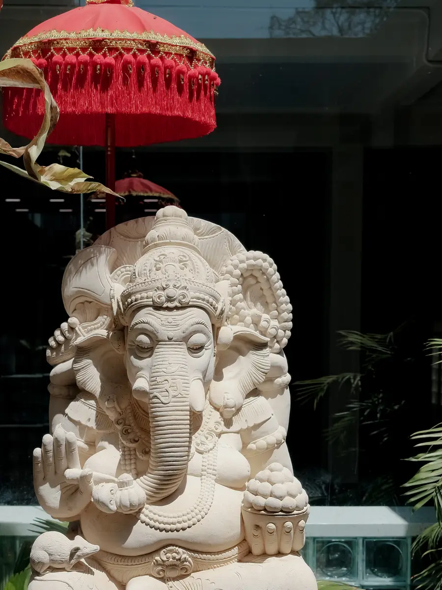 A stone Ganesha under a red Balinese umbrella at the entrance to ASAI GYM