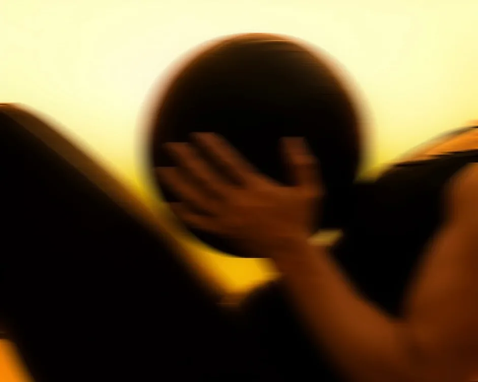 A member holding a medicine ball in silhouette against the amber light of ASAI GYM