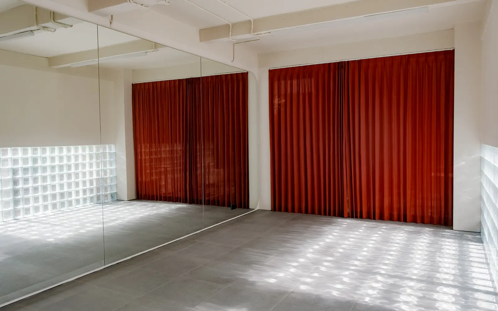 The empty studio at ASAI GYM — red curtains, mirrors and a glass-block wall